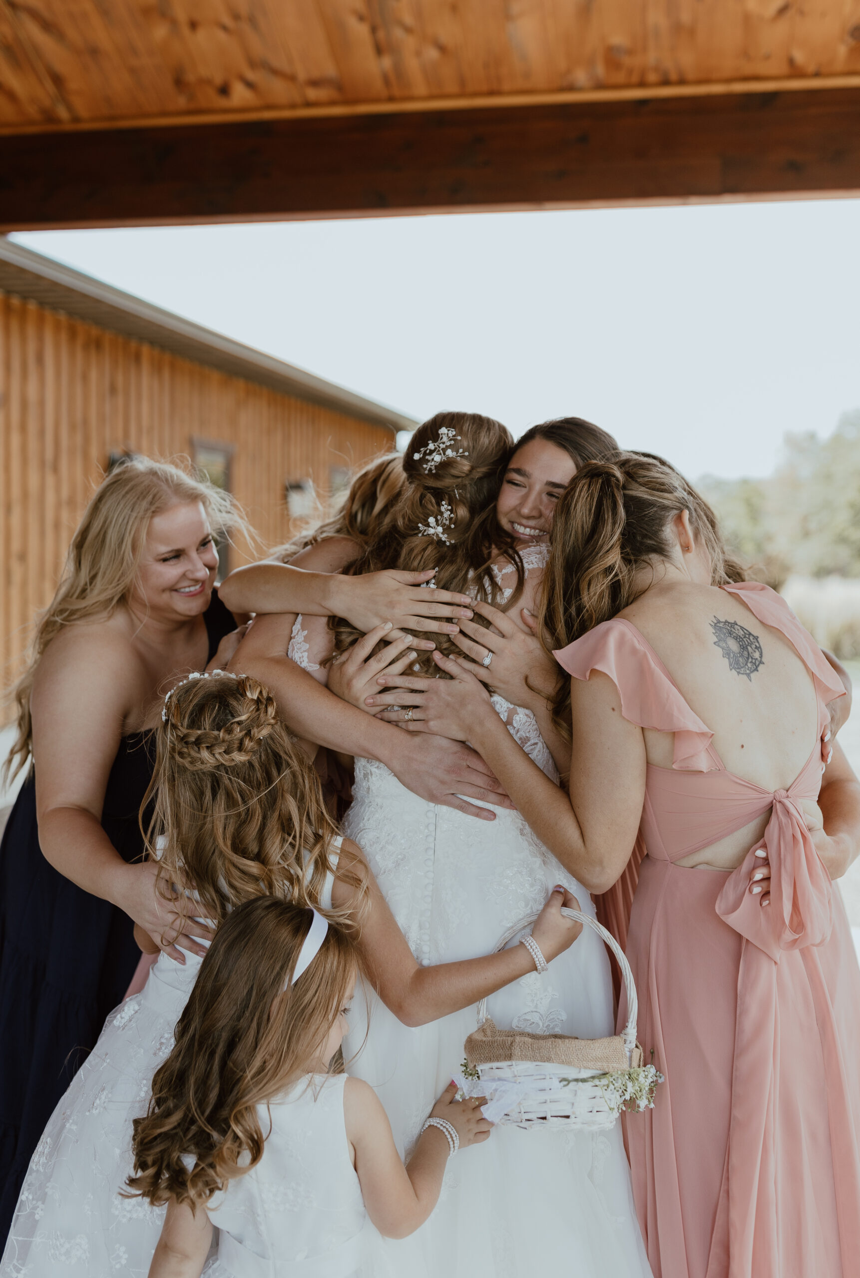 bridesmaids first look hugging with bride on wedding day